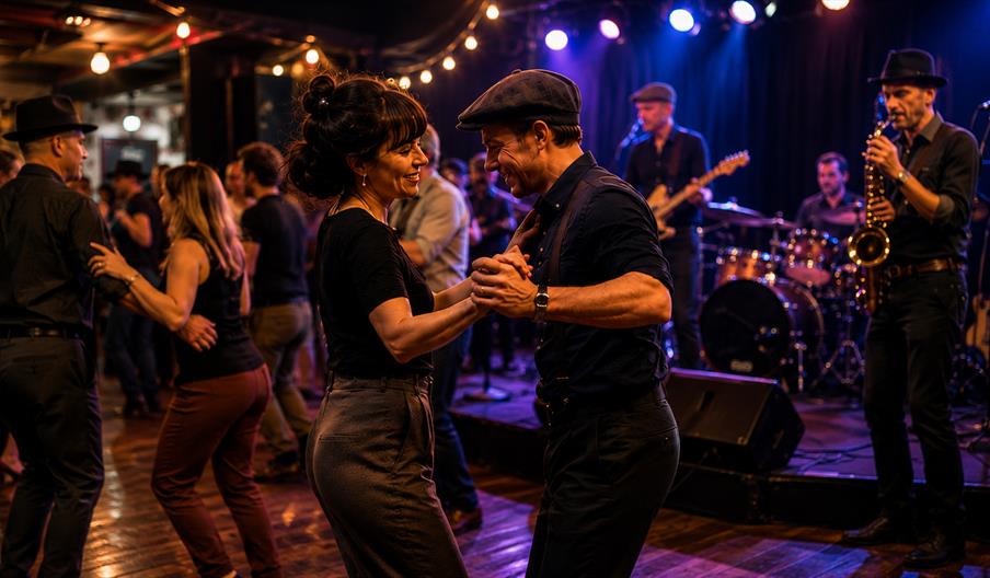 Couples Blues dancing to a live band at an atmospheric evening event.