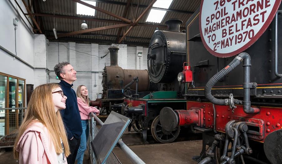 Three people looking up at old trains