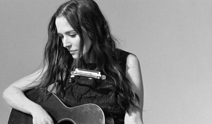 Margaret Glaspy sitting on ground playing guitar