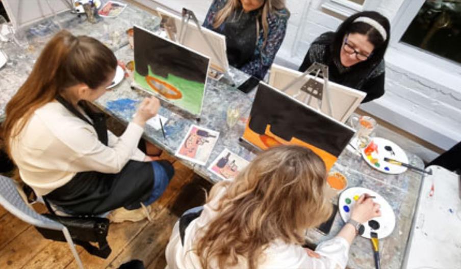 A group of people painting on art canvases
