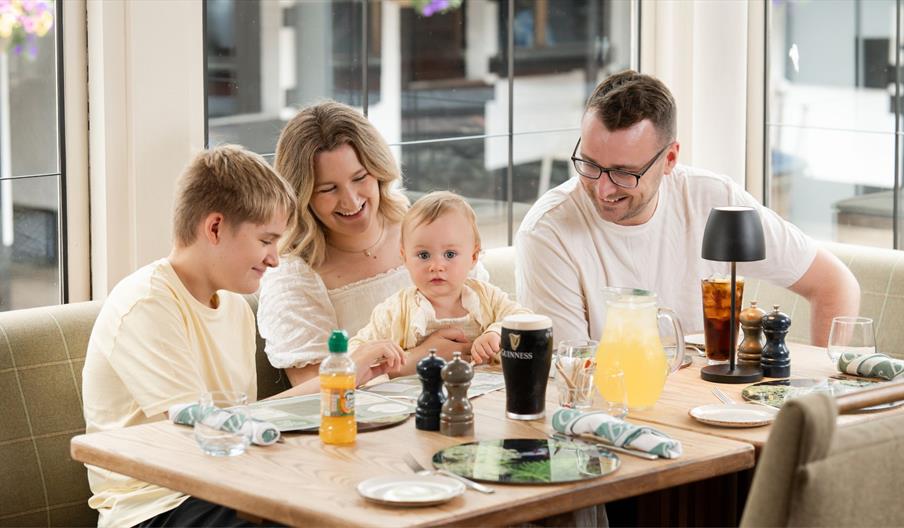 A family enjoying Sunday Dinner in Gillies Restaurant by the windows overlooking the stables