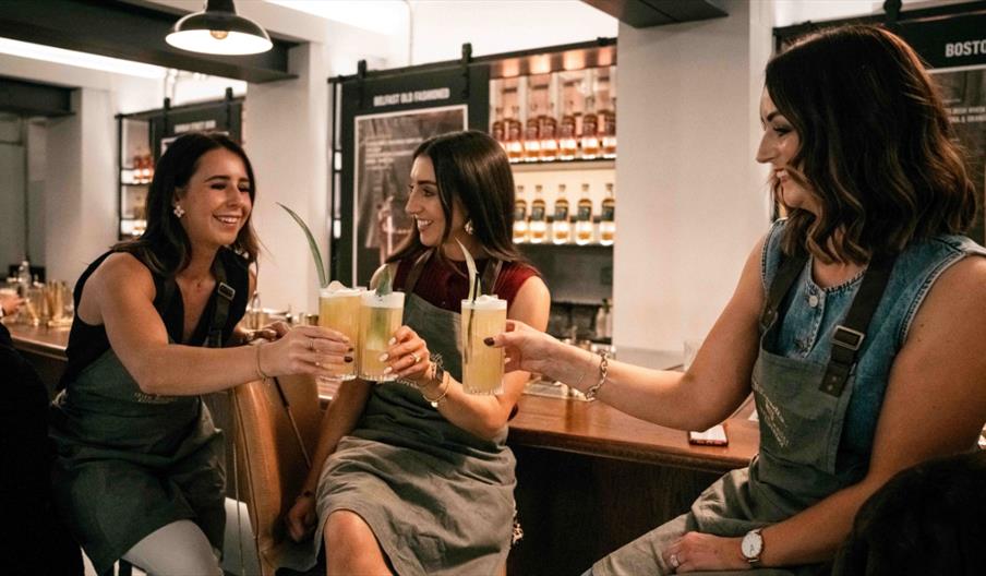 Three ladies raising a glass with their cocktails in the Long Serve Bar.