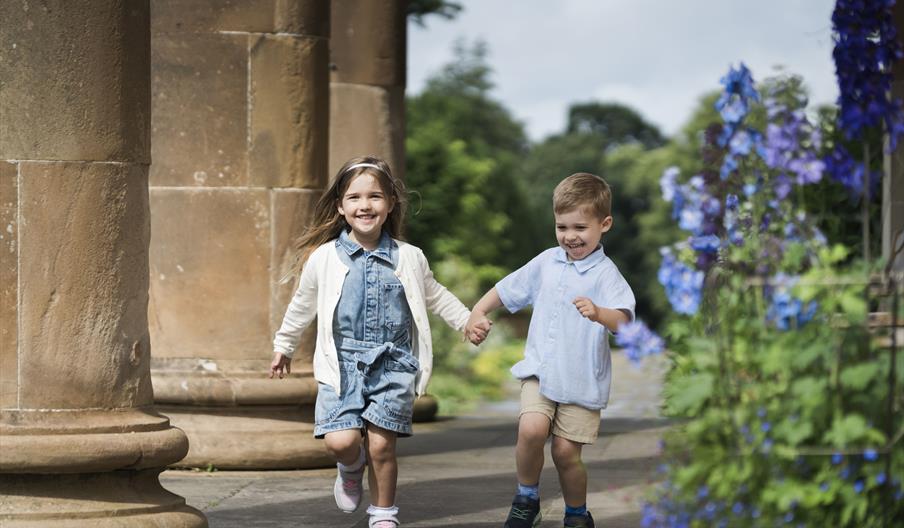 two little children running happy by the beautiful surroundings of Hillsborough Castle and Gardens.