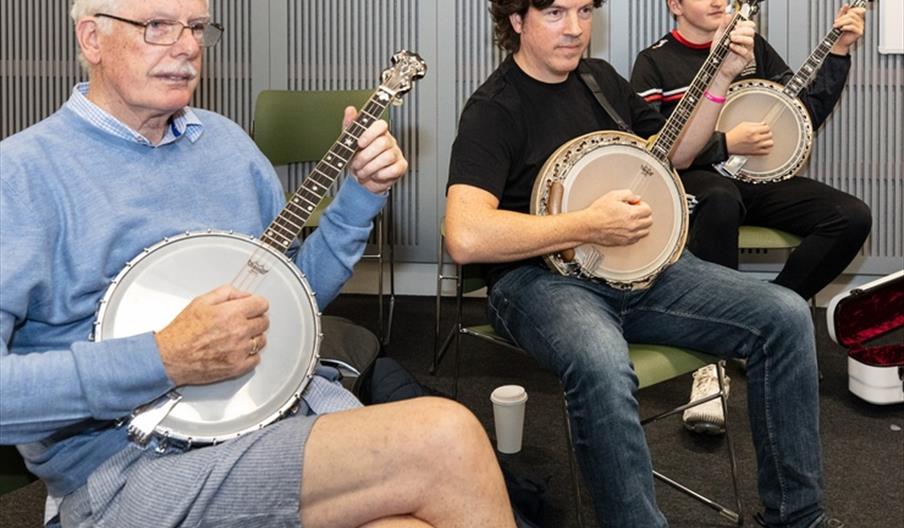 3 people sitting together playing banjos