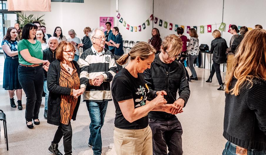 A group of people, all in pairs, participating in a Céilí Dancing Workshopin
