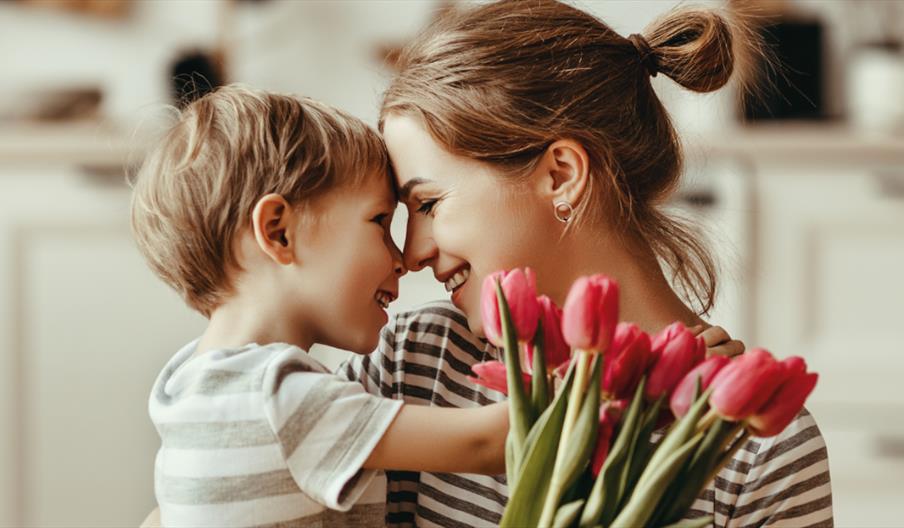 a mother hugging her son and holding a bouquet of tulips