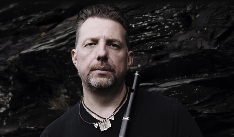 A man holding a flute looking straight ahead