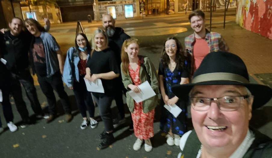 Tour group photo taken at night on a city street.