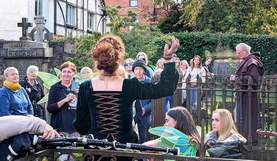 A woman addresses the tour group gathered in the historic cemetery