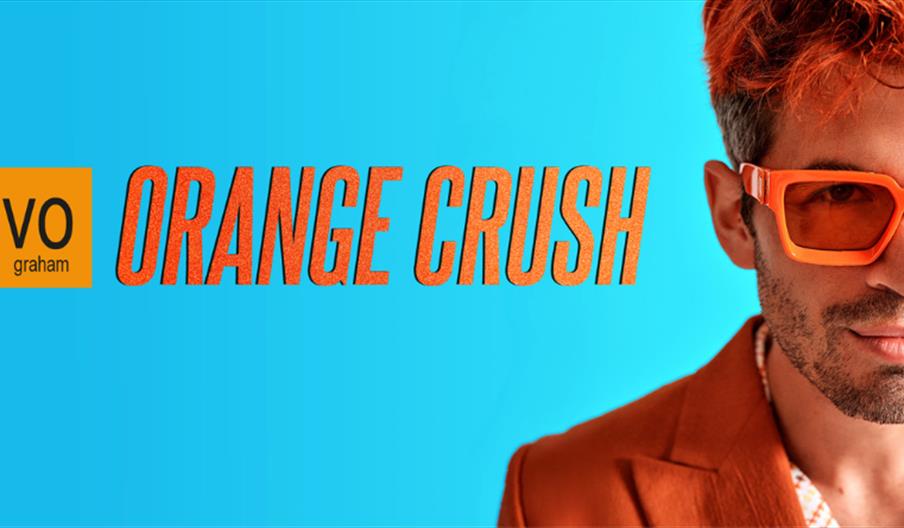 Blue background with 'Orange Crush' in orange text. Ivo Graham is pictured on the right with orange hair, sunglasses, and suit.