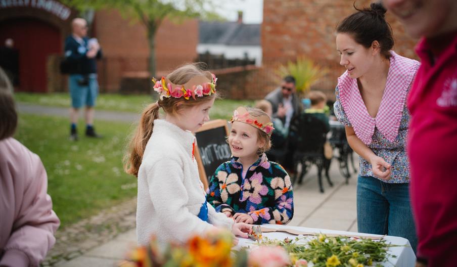 Two girls making flower crowns at the ulster folk museum