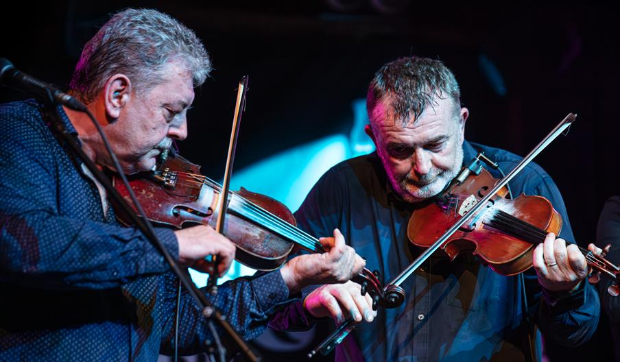 Two of The Bow Brothers playing the fiddle on stage