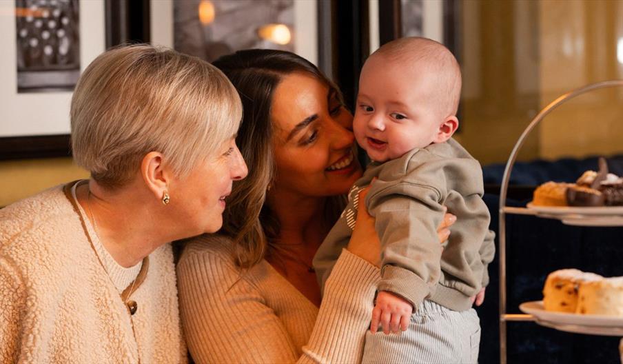 Granny, mum and baby boy in parisien with afternoon tea beside them
