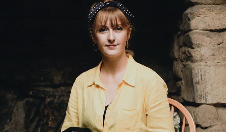 A woman looking ahead wearing a yellow shirt and a bandana