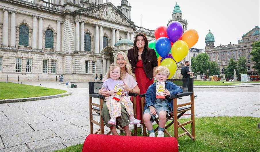 Two adults and two children smile to the camera to launch the 2026 Belfast One Summer Cinema events at Belfast City Hall