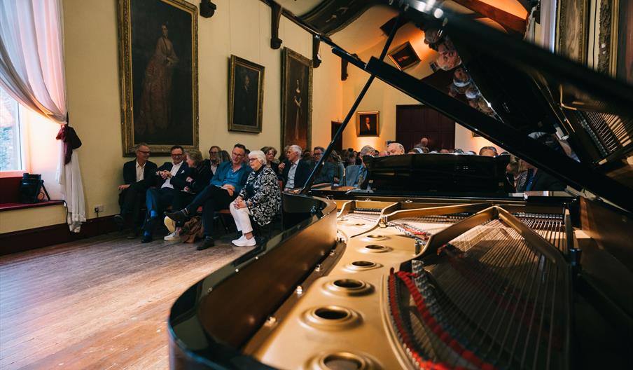 Close up of piano with audience in background