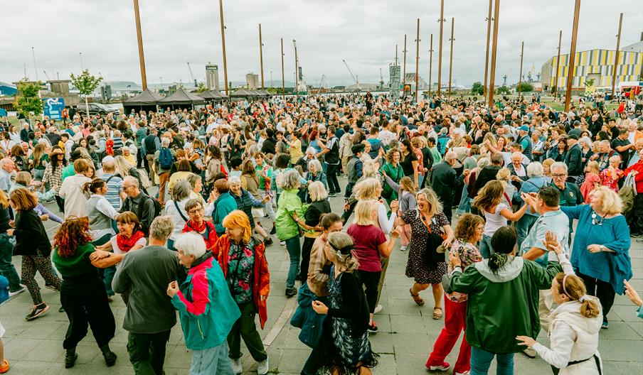A large group of people dancing on the iconic Belfast Titanic Slipways