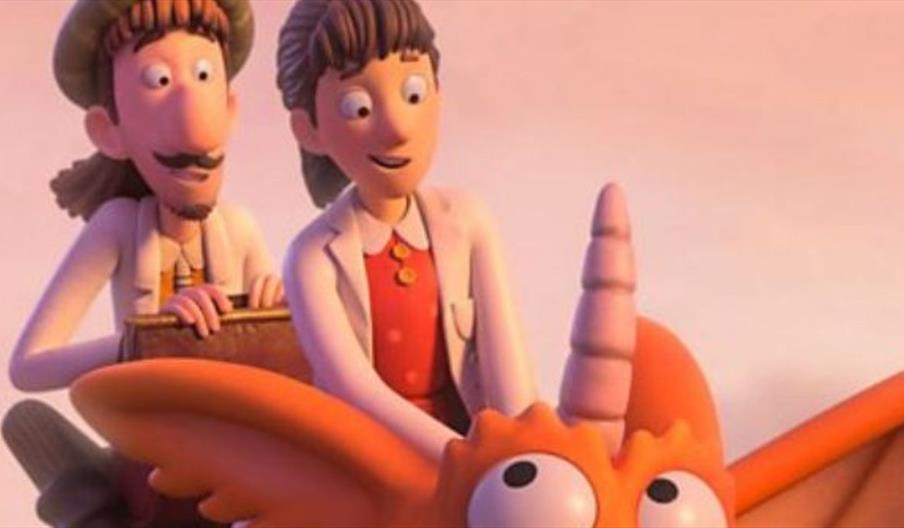 A cheerful orange dragon with wide eyes and a long snout flies through a pink sunset sky, carrying two animated human characters on its back.
