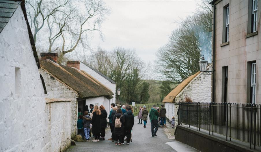 A group of people looking into a white cottage at the ulster folk museum