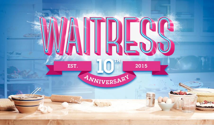 "Waitress 10th Anniversary banner above a kitchen counter with baking ingredients. Tone is cheerful and celebratory, with blue and pink hues."