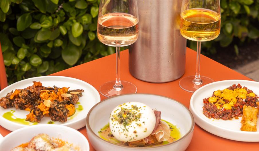 Table set up with small plates including: Tenderstem broccoli, Tomato and Basil Polpette, Burrata, steak tartare, and Charred Hispi Cabbage.