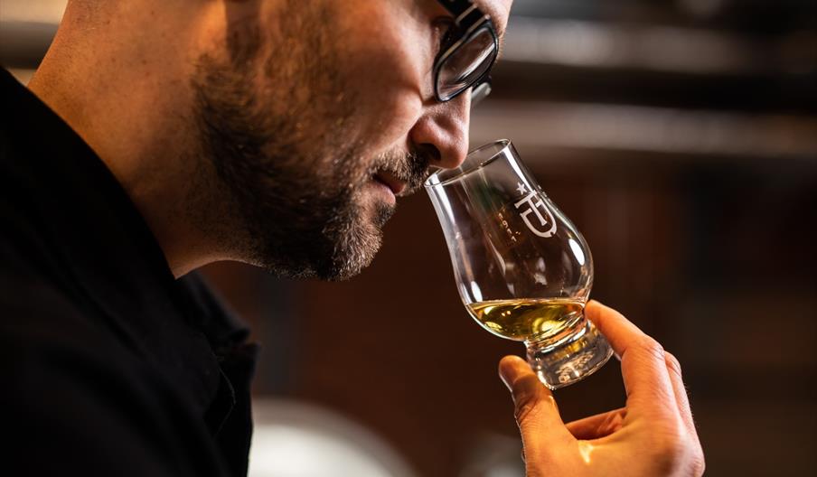 A man smelling a glass ofwhiskey in a tasting room.