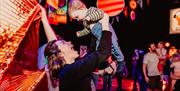 woman holds her baby in the air on dance floor at Baby Rave.