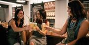 Three ladies raising a glass with their cocktails in the Long Serve Bar.
