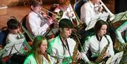Students in a school concert playing saxophones and trombones during a live performance.