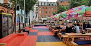 Picture shows people sitting outside at the yellow red and blue flaxx deck