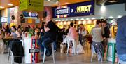 Picture shows people sitting around eating and drinking in the market