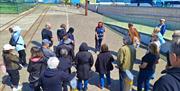 Tour guide showing tourists Titanic dry dock with Titanic studios in backgorund